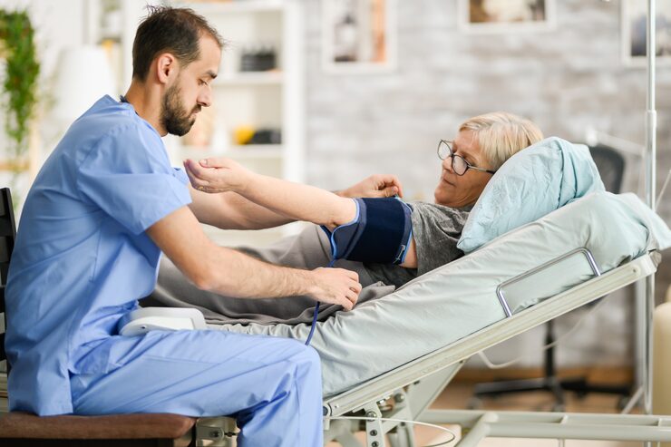 young-male-doctor-taking-blood-pressure-senior-woman-nursing-home_482257-22841